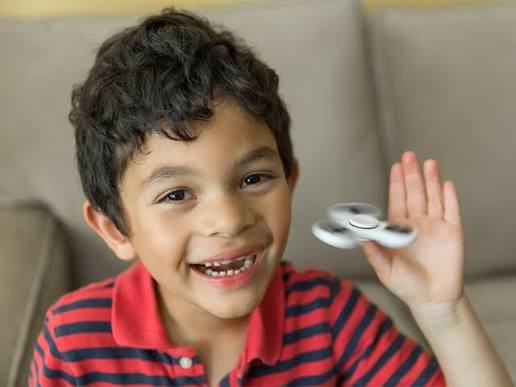Chłopiec z fidget spinnerem — stymulacja sensoryczna jako forma regulacji nadaktywności psychoruchowej u dzieci z ADHD