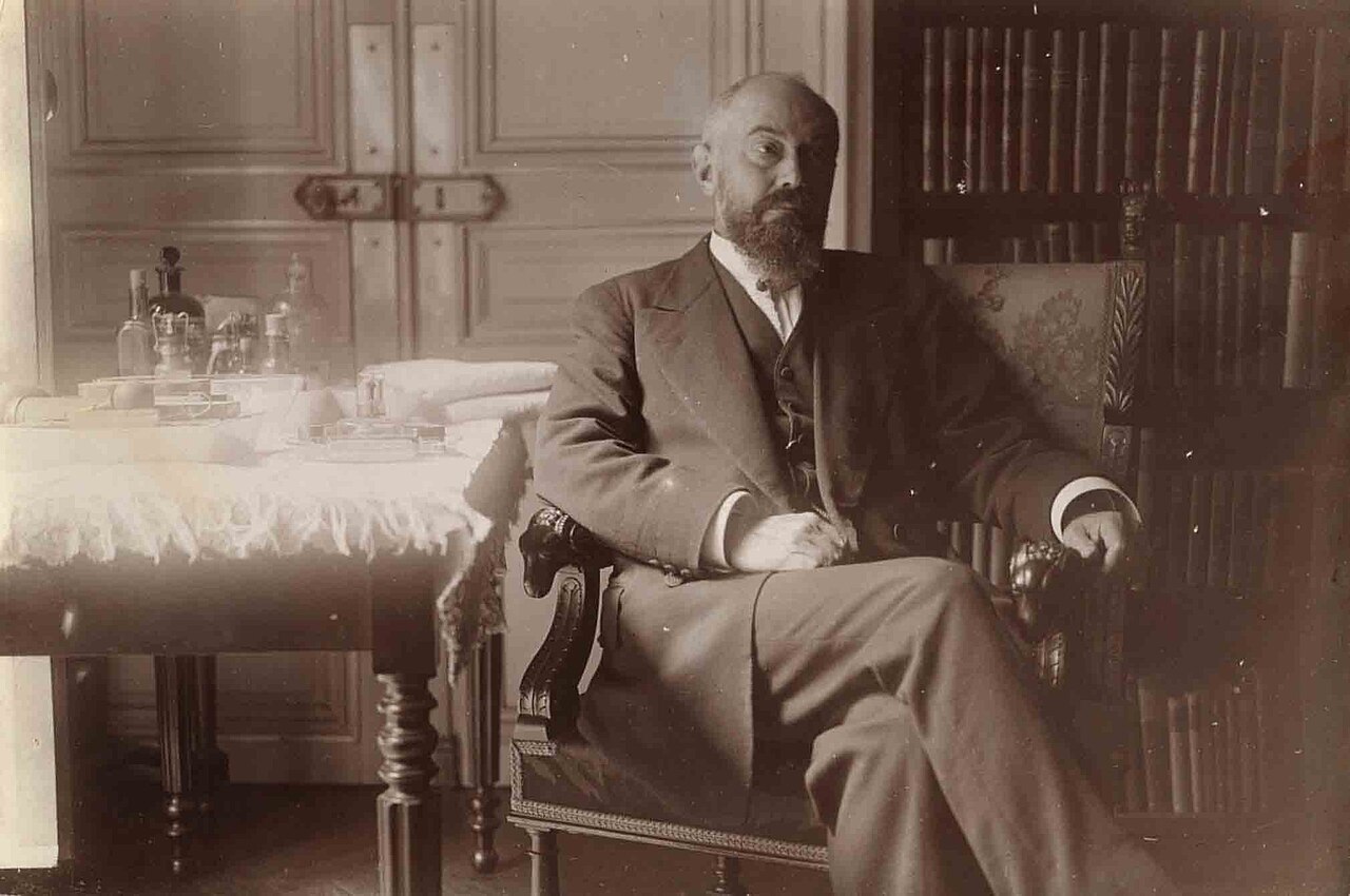 Pierre Janet siedzacy w fotelu w gabinecie z biblioteka - archiwalna fotografia w sepii